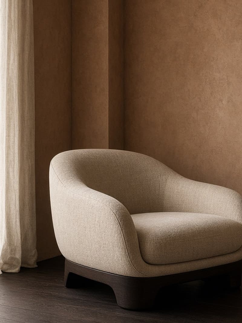 A rounded bouclé armchair beside sheer curtains